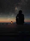 Man sitting under a starry night sky